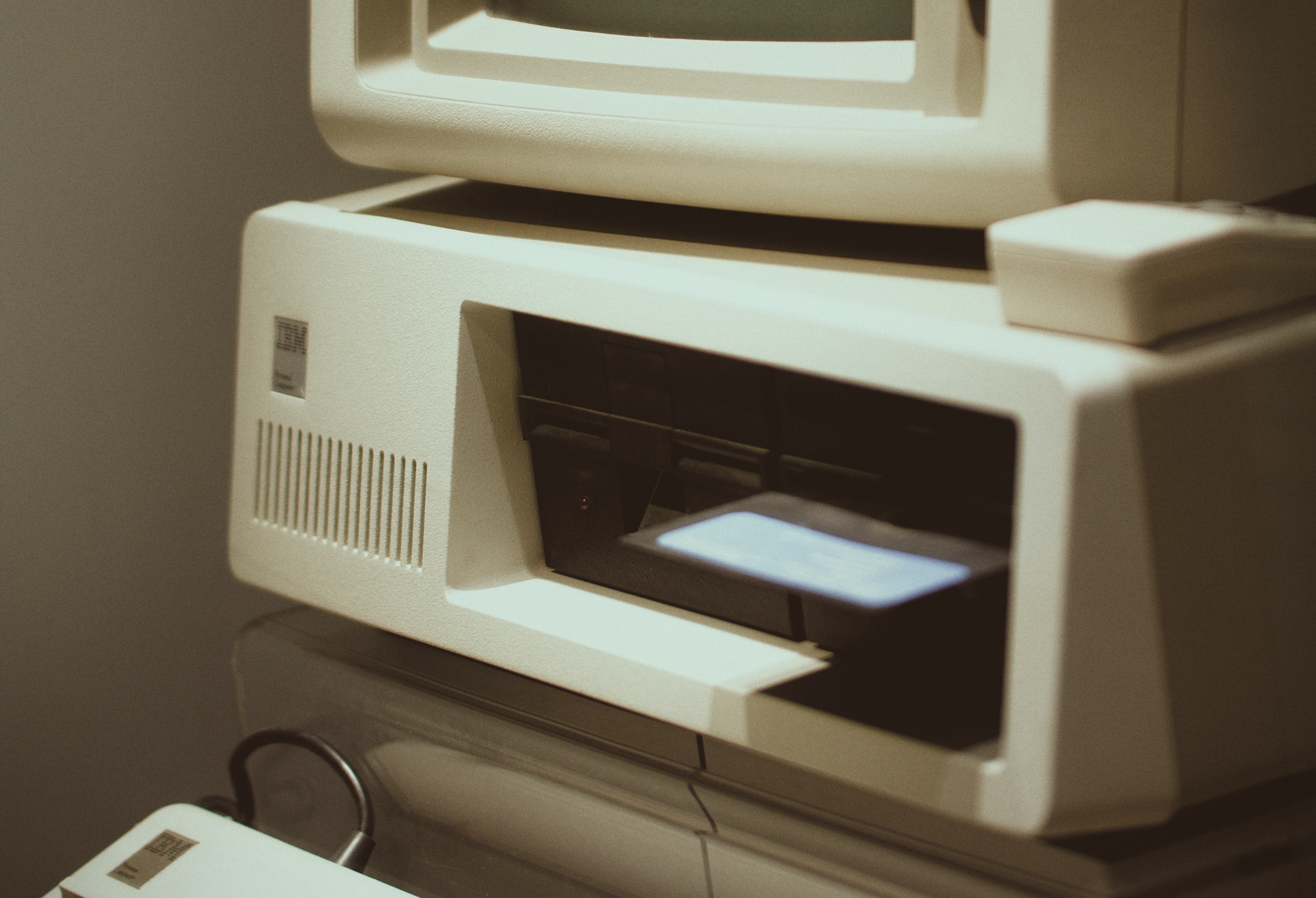 A vintage IBM PC with floppy disk sticking out of the drive